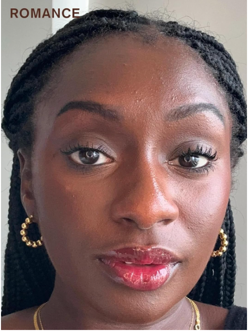 Woman with braided hair wearing gold hoop earrings and a necklace, with the word 'ROMANCE' above her head.