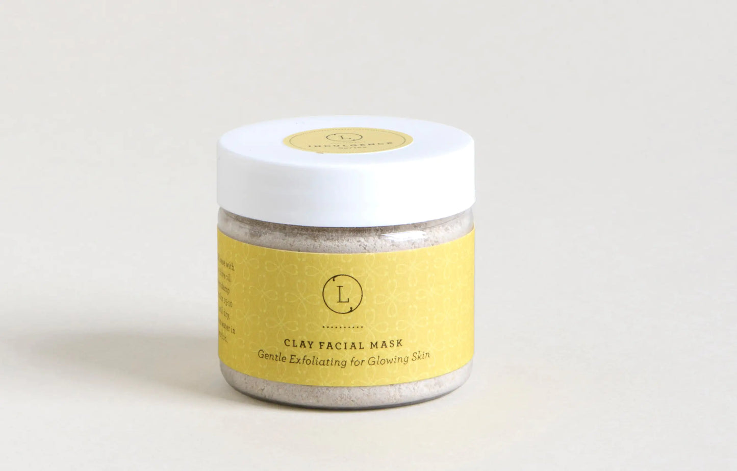 Jar of clay facial mask with a yellow label on a light gray background