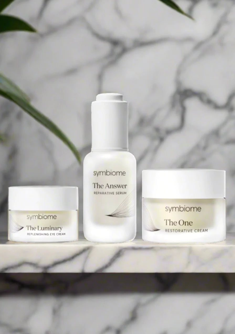 Symbiome skincare products on a marble surface with a blurred natural background