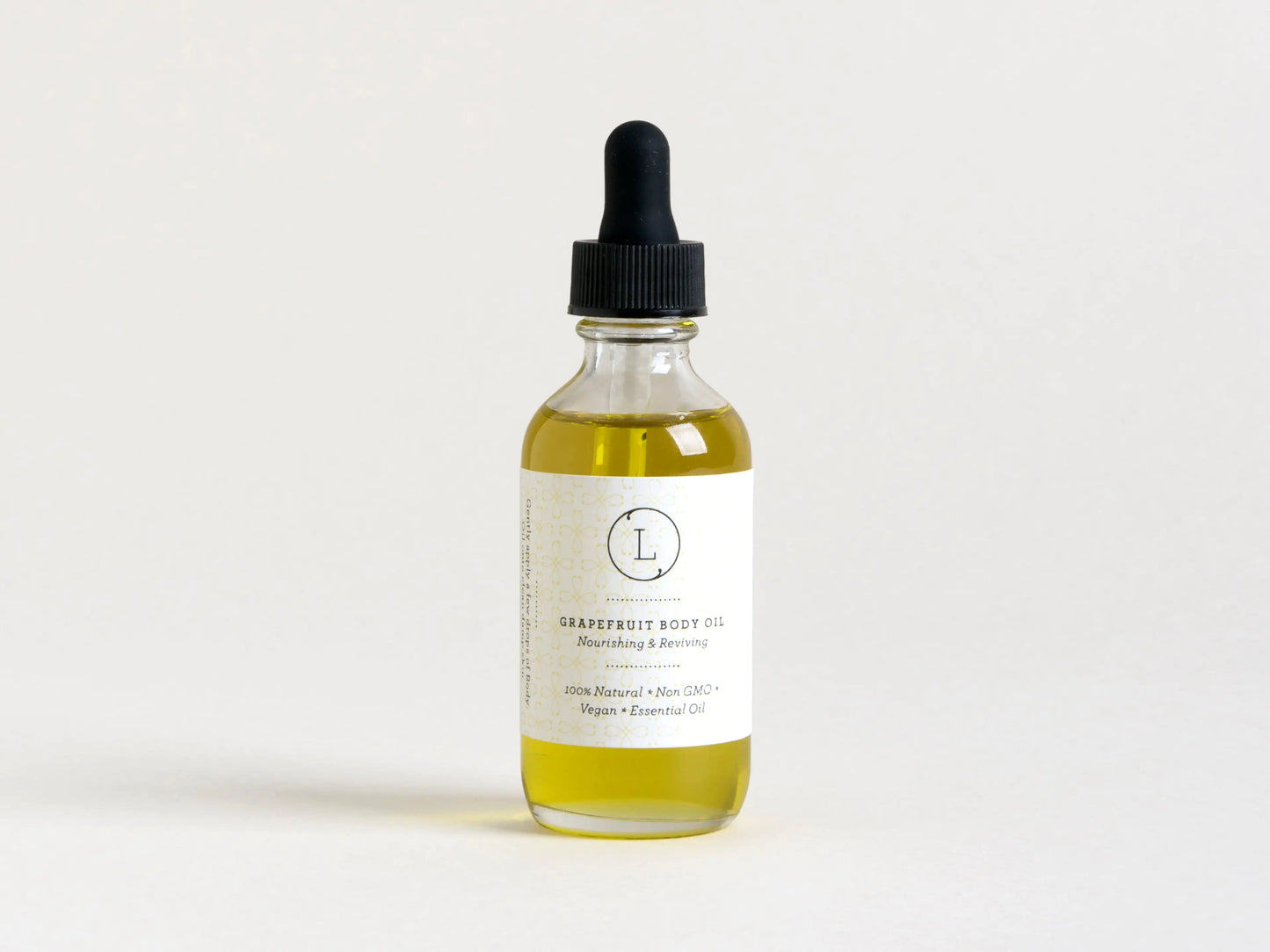 Bottle of grapefruit body oil with a dropper on a white background