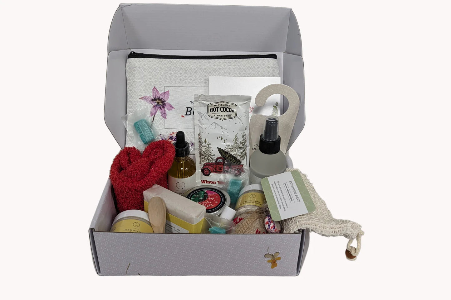 Gift box with various items including a red heart, soap, and a pouch on a white background