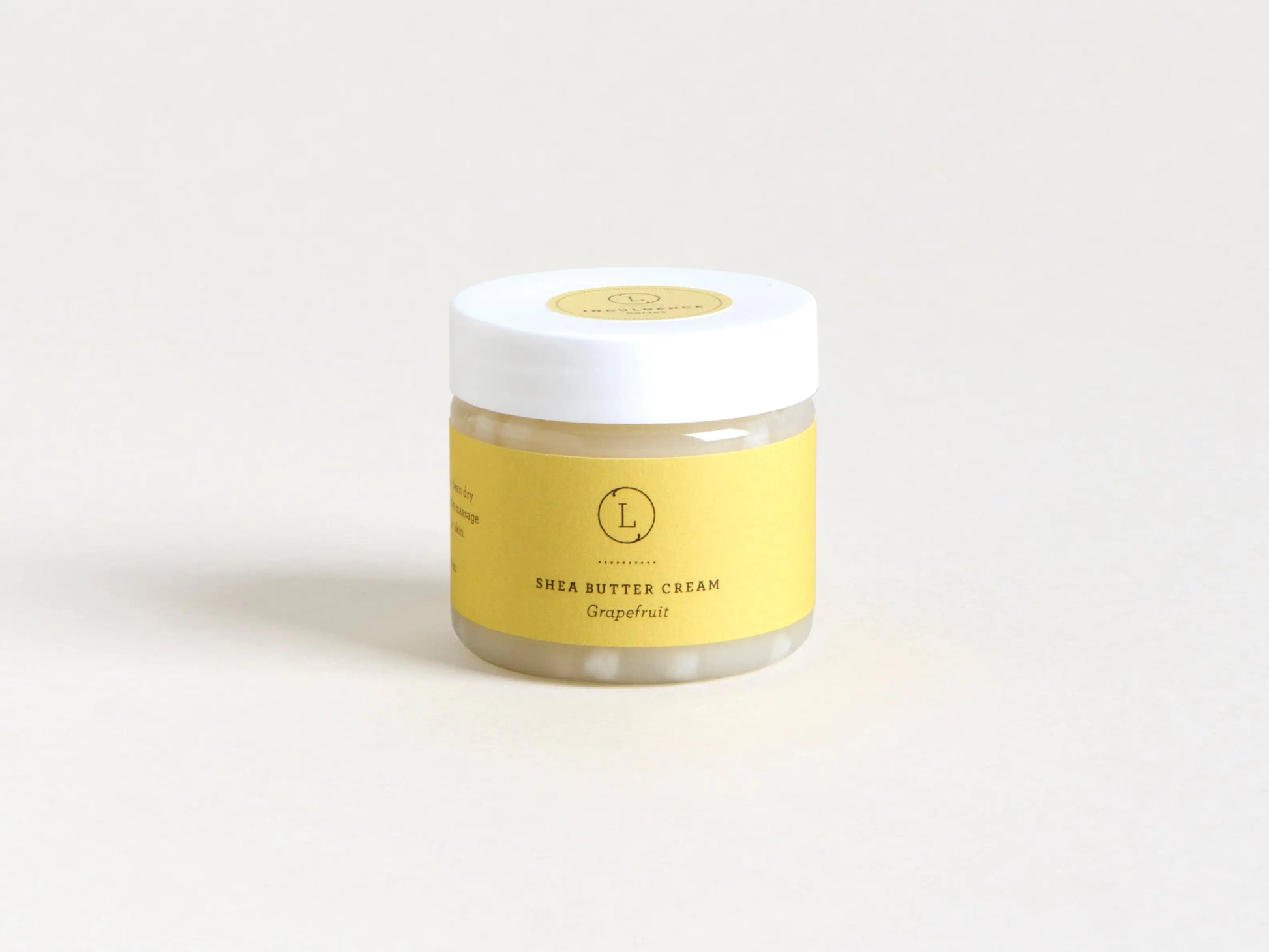 Jar of shea butter cream with a yellow label on a white background