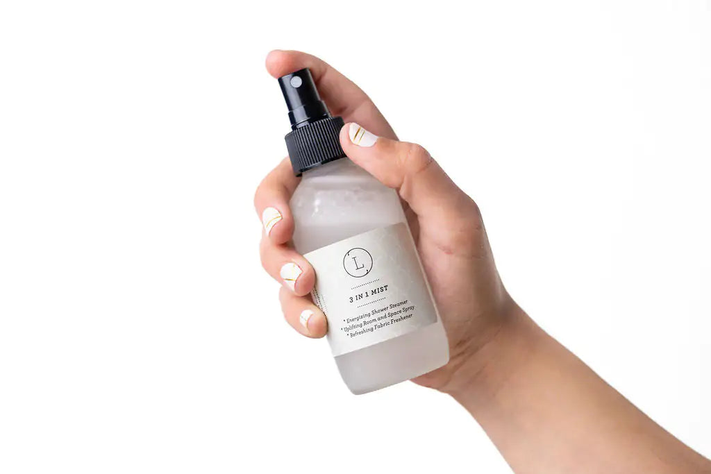Hand holding a spray bottle with a white label against a white background